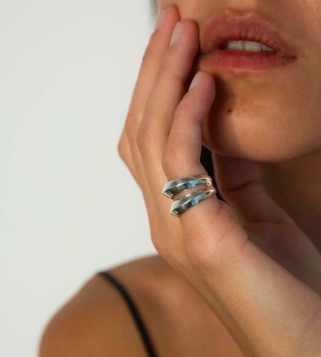 Close up of Lavin double band silver ring on hand near face